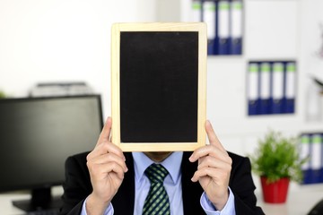 Mann im Anzug hält Tafel vor den Kopf
