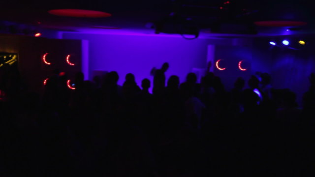 Dark silhouettes of happy nightclub visitors and playing DJ. Party atmosphere