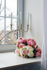 Bouquet of white and pink flowers with candles near the window.
