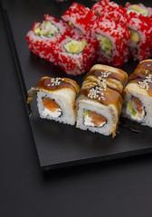 Sushi set on a black plate over dark background