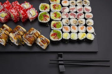 Sushi set on a black plate over dark background