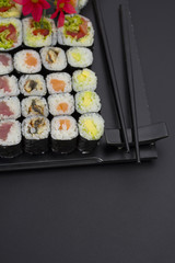 Sushi set on a black plate over dark background