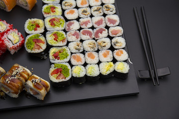 Sushi set on a black plate over dark background