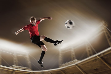 Athlete kicking soccer ball in stadium