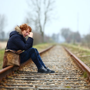 depression/ depressed woman sitting on a train track seeing no way out
