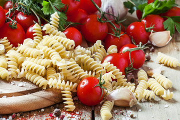Dry pasta fusilli with tomatoes, selective focus