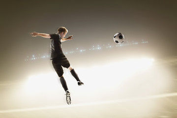 Fototapeta na wymiar Athlete kicking soccer ball in stadium