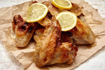 fried chicken wings with lemon on old wooden background