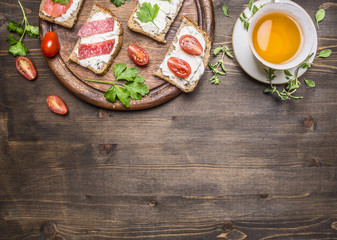 fish sandwiches and salami, with tea border ,place for text  on wooden rustic background top view