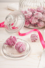Homemade pink marshmallow on a white wooden background.