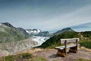 Fotobehang Scenic view on Great Aletsch Glacier in Switzerland with bench in foreground and blue sky with clouds in background. © Ekaterina Grivet