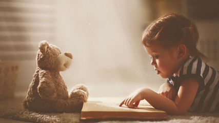 child little girl reading a magic book in dark home