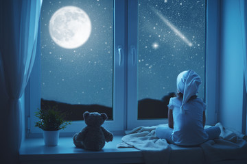 child little girl at window dreaming and admiring starry sky at