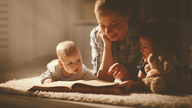 happy family mother and children read a book in evening