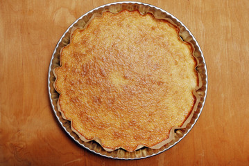 ruddy pie in the form of metal on a wooden board