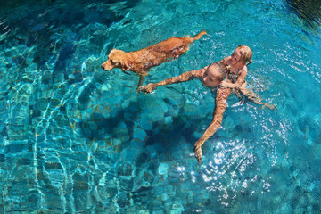 Mother with little child on back play with fun and train golden labrador retriever puppy in...