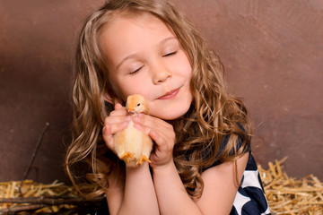 little nice smiling girl hugging alive chicken