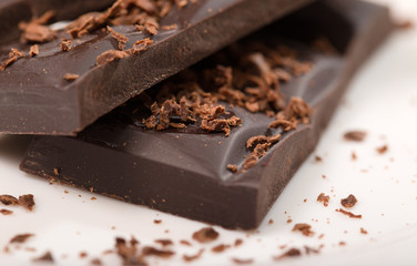 Pieces from a chocolate bar and chocolate crumbs on a white back