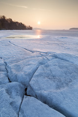Obraz premium Cracked ice at a frozen lake in Finland in the spring at dawn.