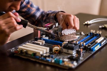 Kid fixes motherboard on table. 