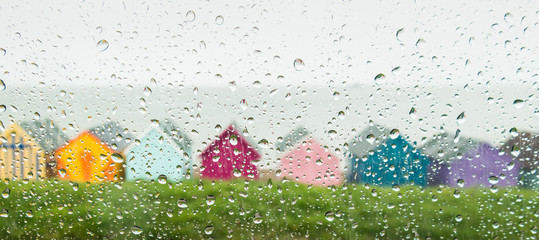 Rain drops on a car window looking at beach huts