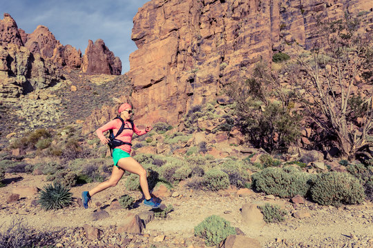Woman trail running in mountains with backpack