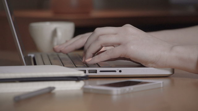 Closeup of a female hands busy typing on a laptop.