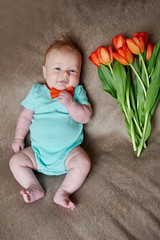 Little boy lying on the bed with a bouquet of tulips