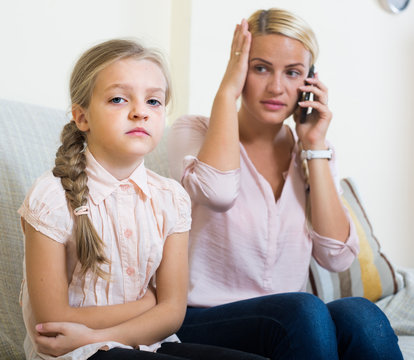 Worried mother calling doctor for daughter with abdominal pains