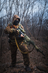 Sniper wearing camouflage suit with rifle walk in the woods