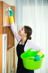 Woman in apron cleaning at home.