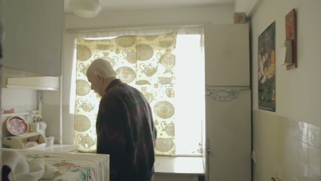 Senior man in glasses and the kitchen is paying attention to something