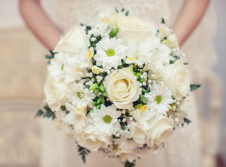 Bride holding white roses and chrysanthemums bouquet in hands