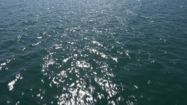 Flying low over water, sun glints in water