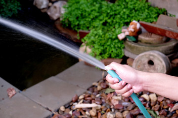 right hand holds blue rubber tubing which have water flows from
