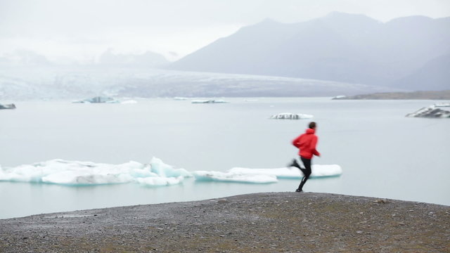 Running man sprinting on trail. Runner in fast sprint in beautiful nature landscape. Fit male athlete sprinter cross country running by icebergs in Jokulsarlon glacial lake in Iceland.