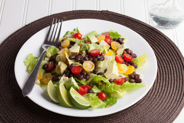 Southwest black bean, lime, cilantro, tomato, and avocado salad on a vintage antique plate top view