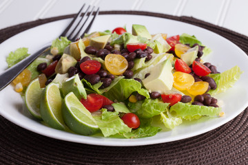 Southwest black bean, lime, cilantro, tomato, and avocado salad on a vintage antique plate macro shot