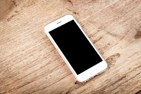 Mobile phone with blank screen mockup isolated on wood table bac