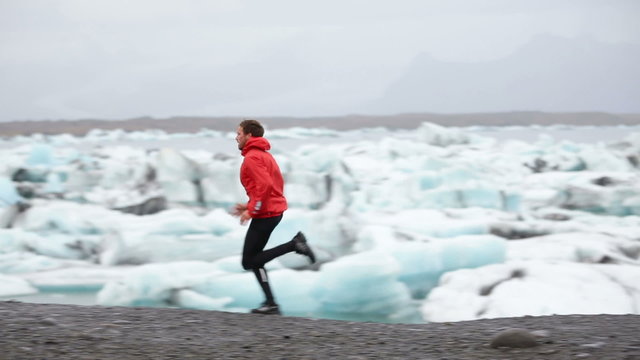 Running man. Sprinting trail runner in fast sprint in beautiful nature landscape. Fit male athlete sprinter cross country running by icebergs in Jokulsarlon glacial lake in Iceland.