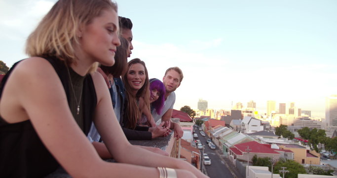 Happy friends watching the sunset over the city from rooftop