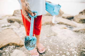 cropped image  a girl standing on the beach holding blue toy cov