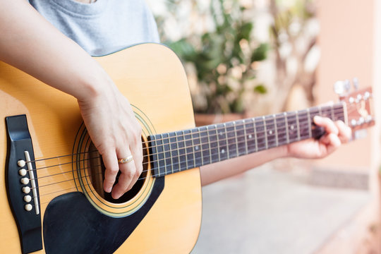 Woman's hands playing acoustic guitar
