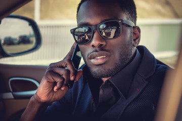 Black man in sunglasses talking by smartphone.