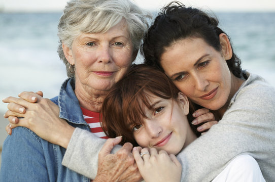 Three generations of women hugging on beach