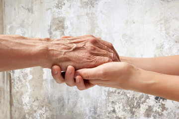 Hands of an elderly man holding the hand of a woman