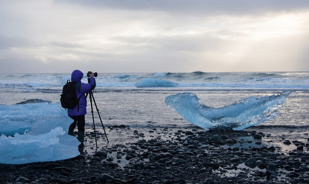 photographer is shooting a photo on the ice beach in iceland