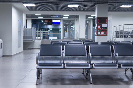 Waiting zone in an airport with grey chairs.