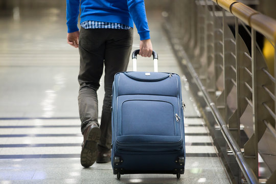 Traveler pulling suitcase close-up