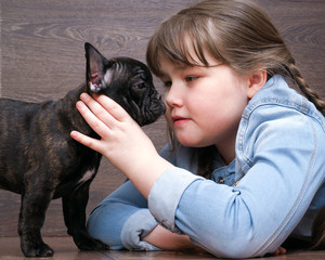 Girl and dog. The girl's face and a large muzzle puppy. Dog black French Bulldog. The relationship of the child and the dog. Concept - trust, love, the contents of the house dogs 